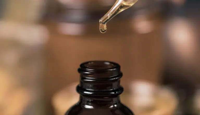 Herbal tincture dropper adding liquid to glass bottle for custom herbal formula